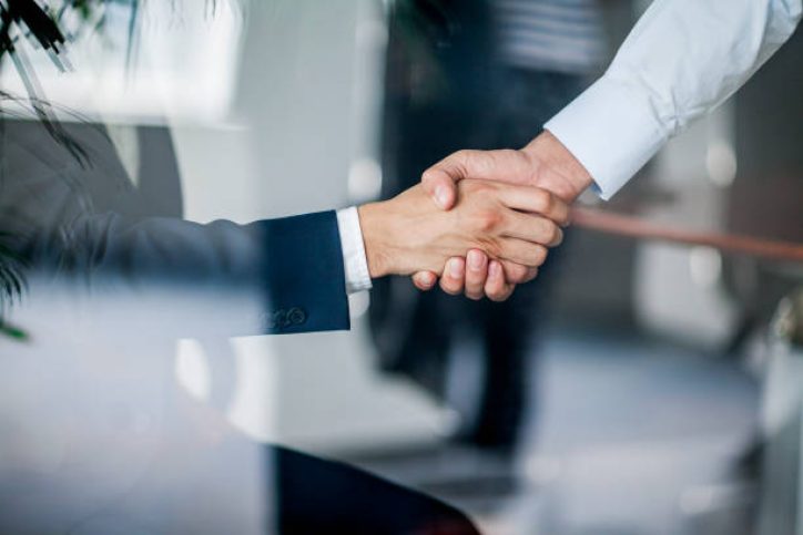 Business handshake in glass reflection in office